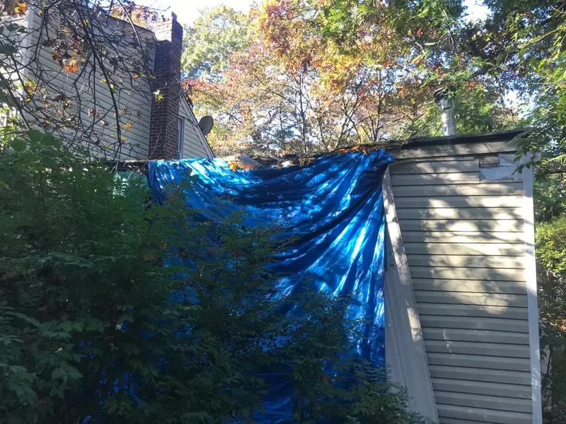 Blue tarp hung over the back of a house, Medford, NY